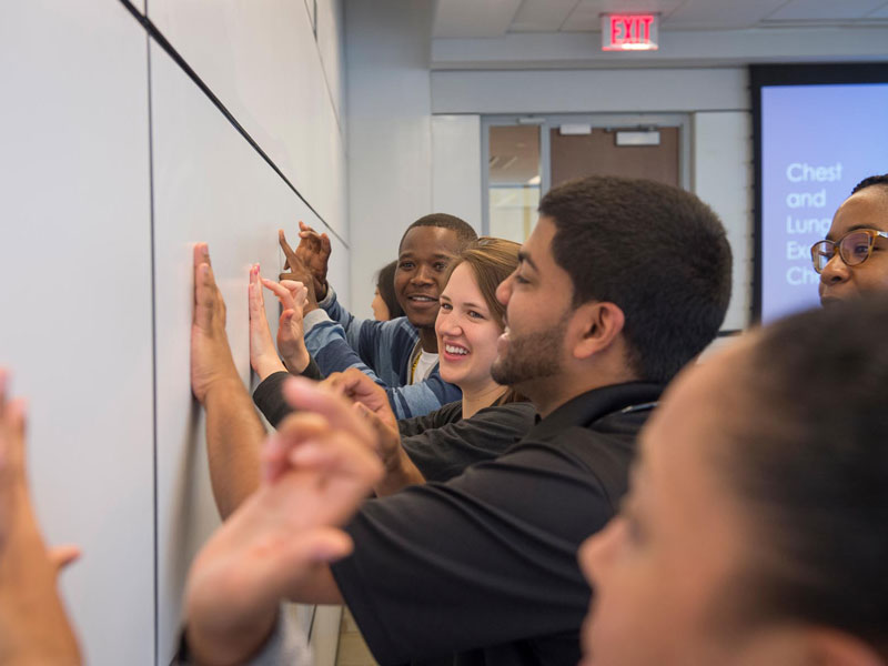 a group of people doing an activity on a whiteboard